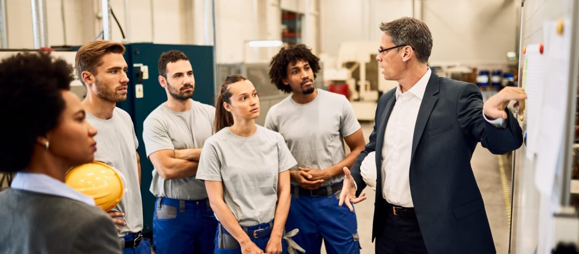 mid-adult-businessman-giving-presentation-group-industrial-workers-factory-min